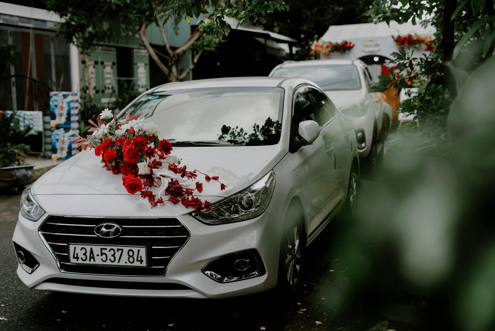 White car adorned with red flowers, perfect for a wedding. Captured outdoors with a Hyundai model.