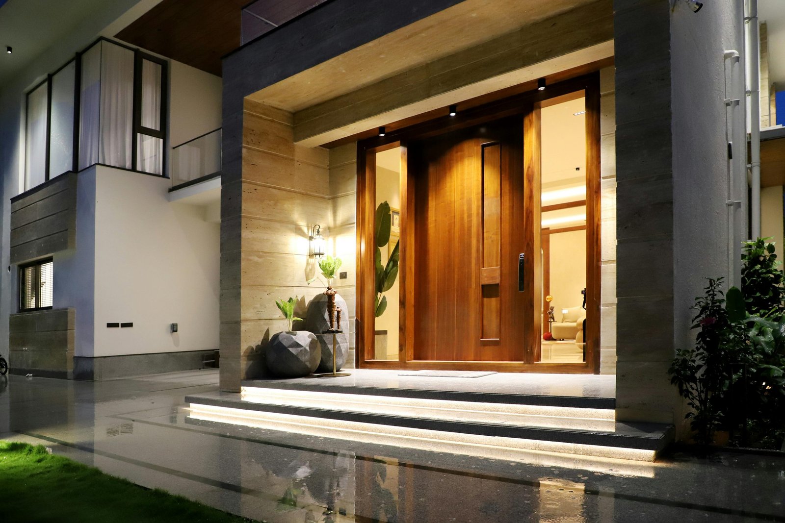 Elegant entrance of a modern house with warm lighting at night, showcasing contemporary architecture.