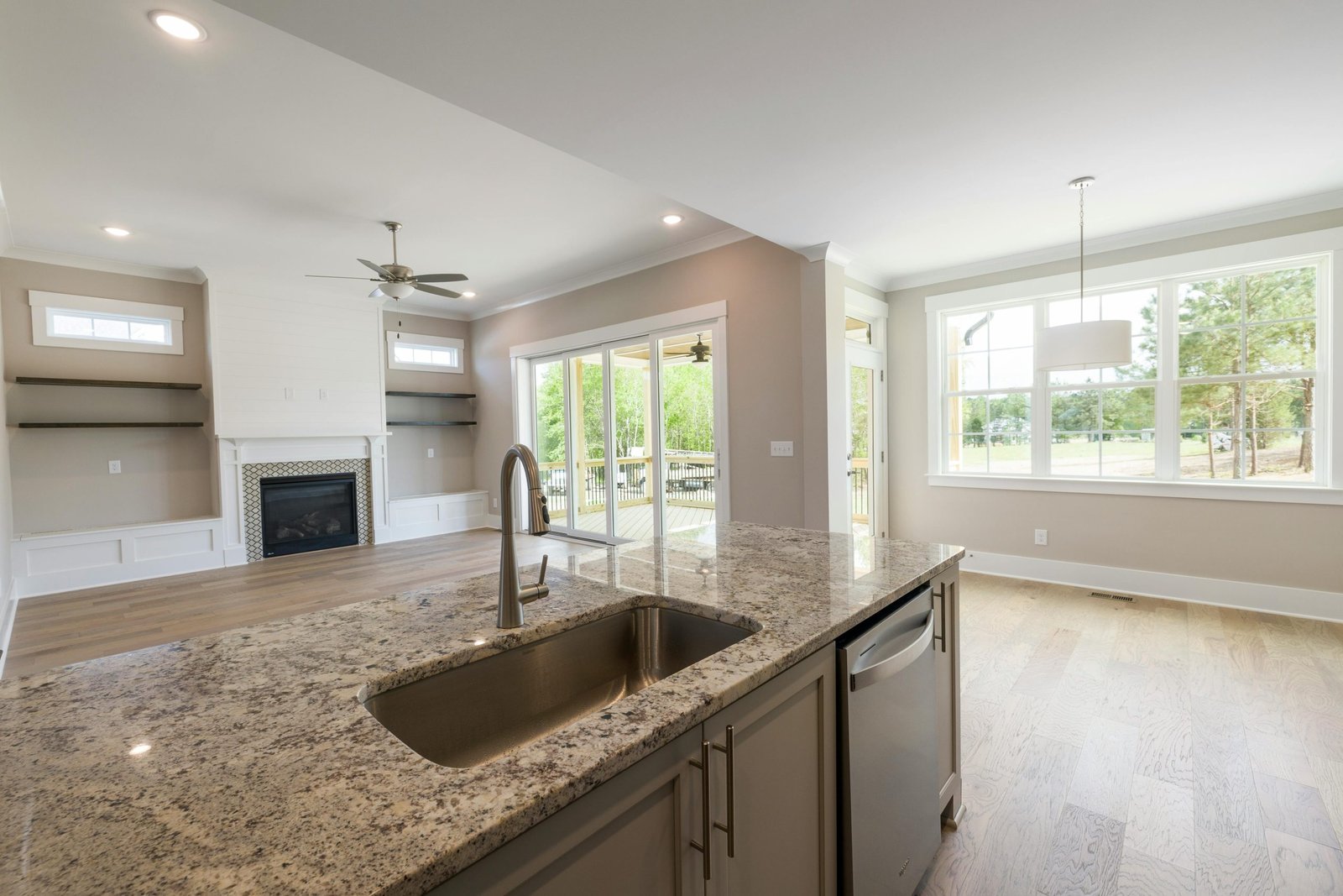 Bright and modern kitchen interior featuring granite countertops, wooden flooring, and ample natural light.