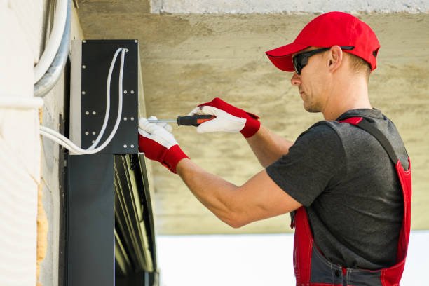 A man in a red shirt and hat repairs a metal roof, demonstrating skills relevant to home maintenance in Fayetteville, GA.