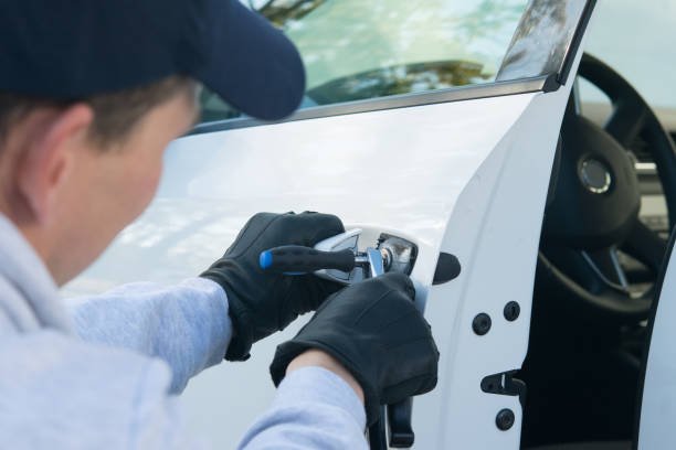 A man in blue overalls with a cell phone, symbolizing locksmith assistance for replacing car keys.