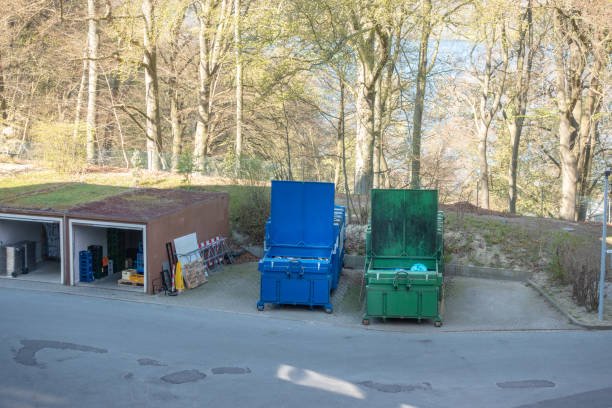 Two green roll-off dumpsters positioned side by side on a concrete surface.