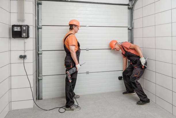 A man in overalls is engaged in fixing a garage door, specifically the spring component