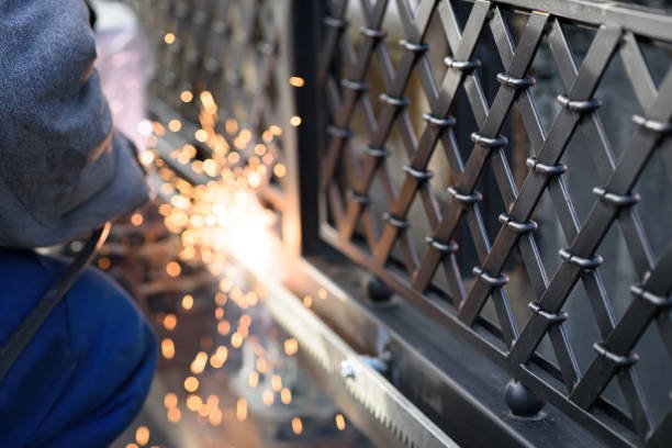 A man works on a metal fence, demonstrating the process of professional fence installation services.
