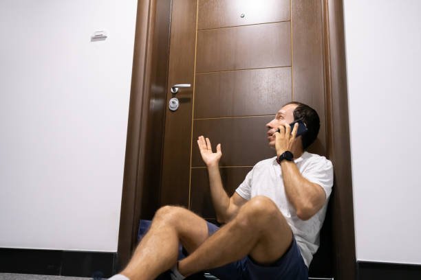A man sitting on the floor in front of a door, possibly waiting for locksmith services in Bossier Parish, LA.
