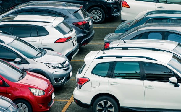 A parking lot filled with a row of used cars and trucks, all parked in an organized manner.