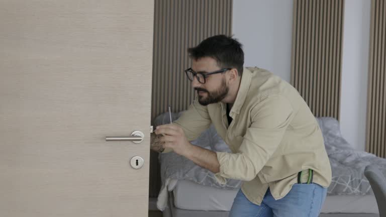 A man wearing glasses and a black shirt is seen opening a door, illustrating the work of Home Lockout Experts.