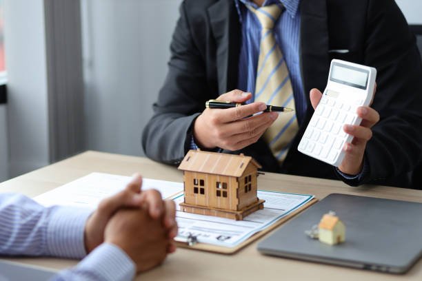 A man and woman, identified as a mortgage broker, sit at a table reviewing papers together.