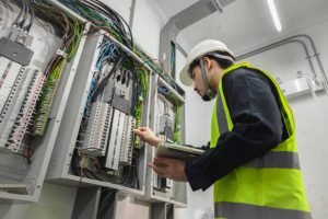 A man in a safety vest inspects an electrical panel, representing commercial electrical services in Bartlett, TN.