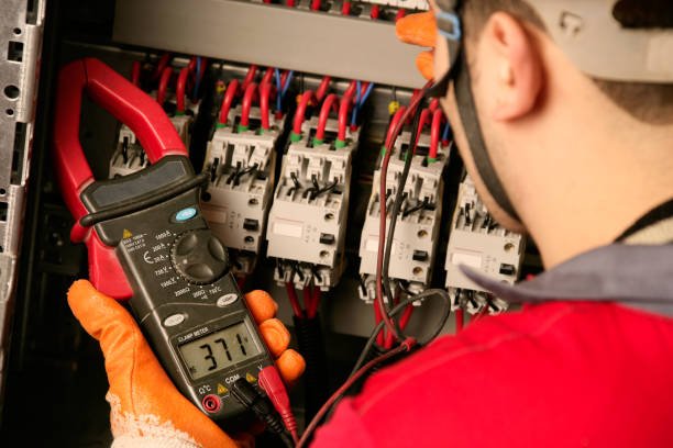 A man in a safety vest studies an electrical panel, showcasing commercial electrical services available in Bartlett, TN.