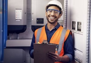 A smiling man in an orange vest holds a clipboard, representing a reliable electrician for home repairs in Collierville, TN.