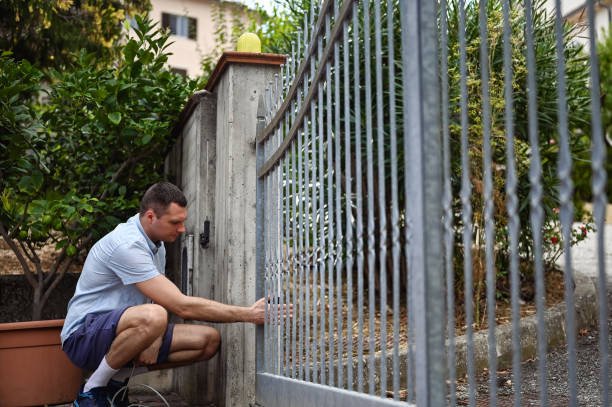A man is engaged in the installation of a metal fence, highlighting fence installation services.