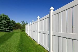 A wooden fence surrounds a backyard with lush green grass, highlighting wood fence installation services.