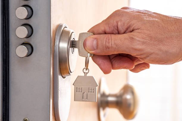 A person using a key to open a door, illustrating locksmith services for home access.