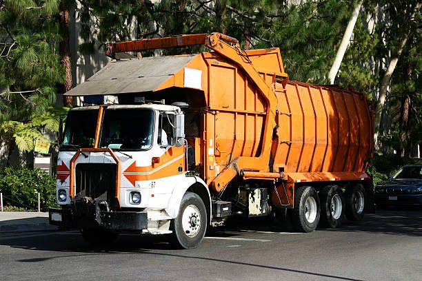 A large orange garbage truck parked, promoting online dumpster rental services.