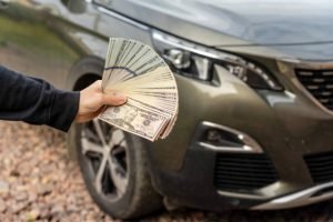 A man holding cash in front of a car, promoting the message to sell your junk car for quick cash.