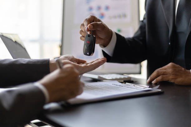Two men stand by a local used car and truck, talking to each other about the vehicle's features and condition.