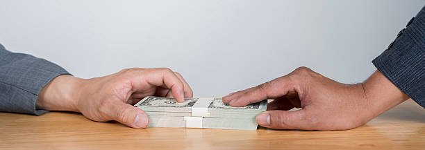 Two hands holding stacks of cash on a table, symbolizing personal loans and financial transactions.