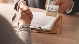 A person and a mortgage lender shaking hands over a desk, illustrating a business agreement near Rock Hill.