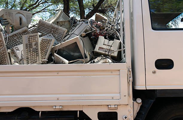 A man with a remote control stands next to a truck overflowing with junk, advertising electronic waste pickup in Franklin, TN.