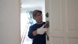 A man in a black shirt and glasses is opening a door, representing the services of Home Lockout Experts.