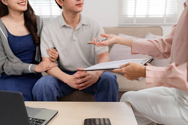  A woman's hand writes on paper with a pen, accompanied by a house model, symbolizing mortgage broker services in Gastonia, NC.
