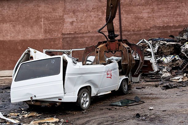 Crane crushing machine destroying a motor vehicle for scrap metal