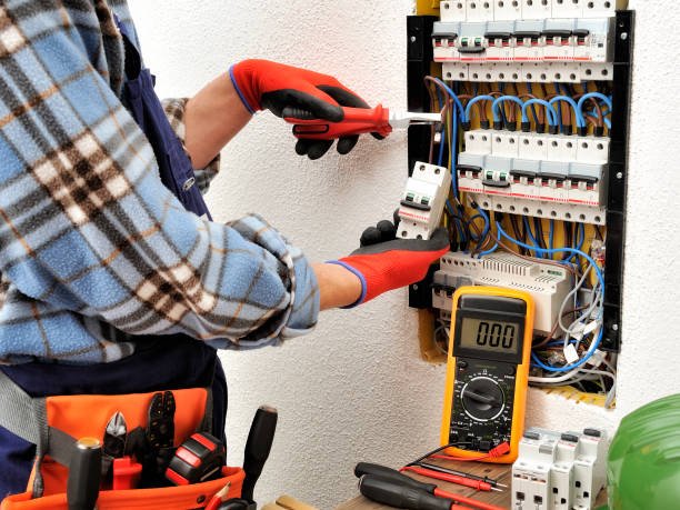 A man uses a multimeter to test a panel, representing commercial electrical services in Bartlett, TN for offices and shops.