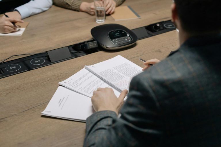 Close-up of business professionals reviewing documents during a meeting in a modern office setting.