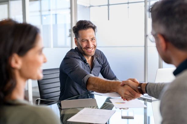 Two business people shaking hands in an office meeting at Our Reliable Funding, representing collaboration and mutual agreement.