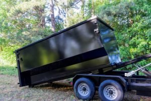 Black dump trailer with a flat bed, promoting fast and affordable dumpster rentals in Downtown Wilmington, NC.