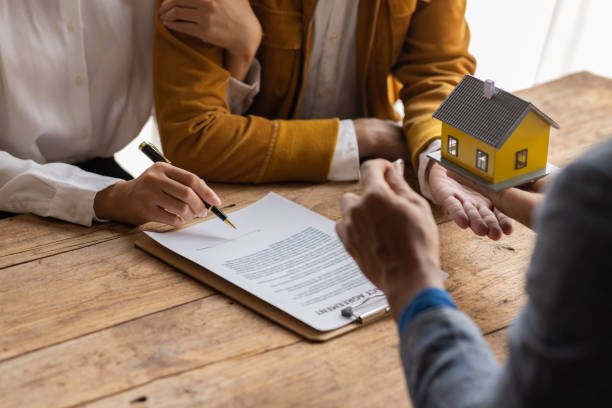 Two businessmen shake hands over a house model, symbolizing a partnership with a trusted mortgage lender.