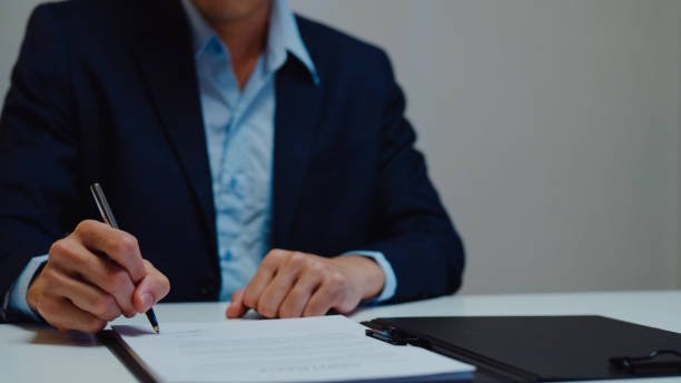 Man engaged in writing on paper with a house model nearby, illustrating real estate funding efforts in Chattanooga, TN.