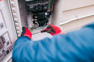 A person fixes a light switch with an electrical device, highlighting top-rated electrical services in Arlington, TN.