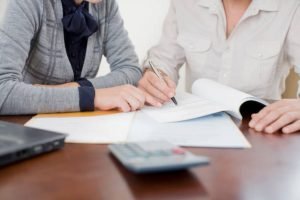 Two individuals sitting at a table, writing notes with a pen and paper, focused on real estate funding in Memphis, TN.
