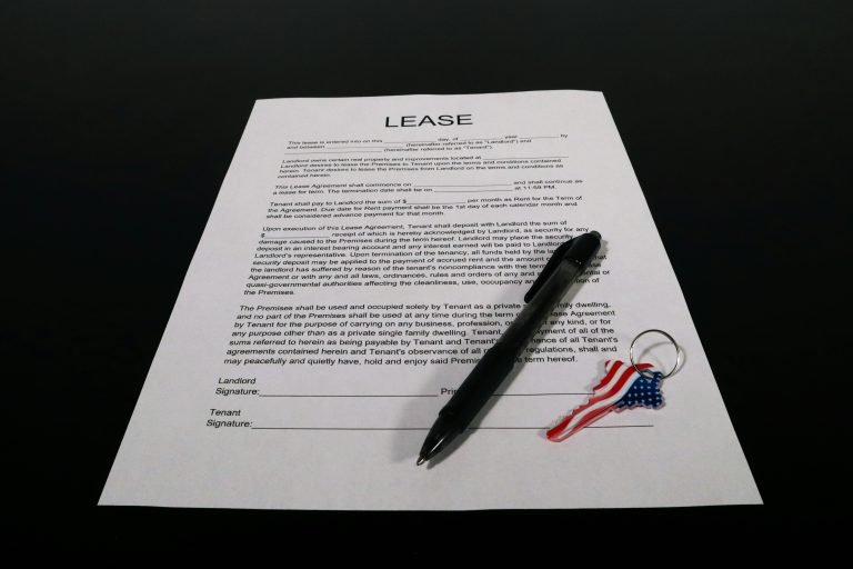 Lease agreement document with pen and American flag keychain on a black table.