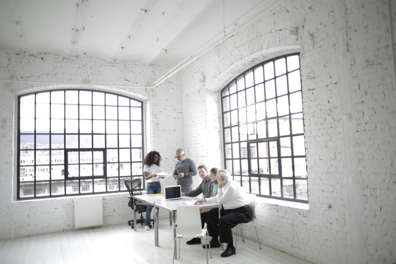 Group of diverse adults collaborating in a modern office with large windows.