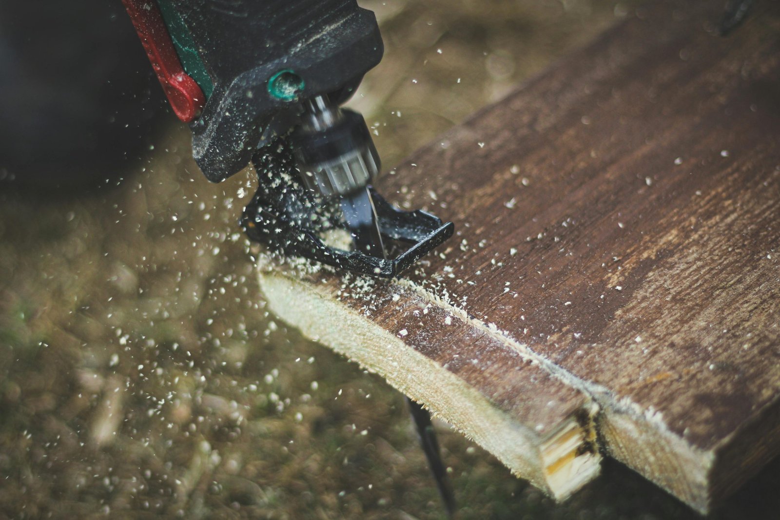 Detailed shot of a power jigsaw cutting wooden plank with sawdust flying.