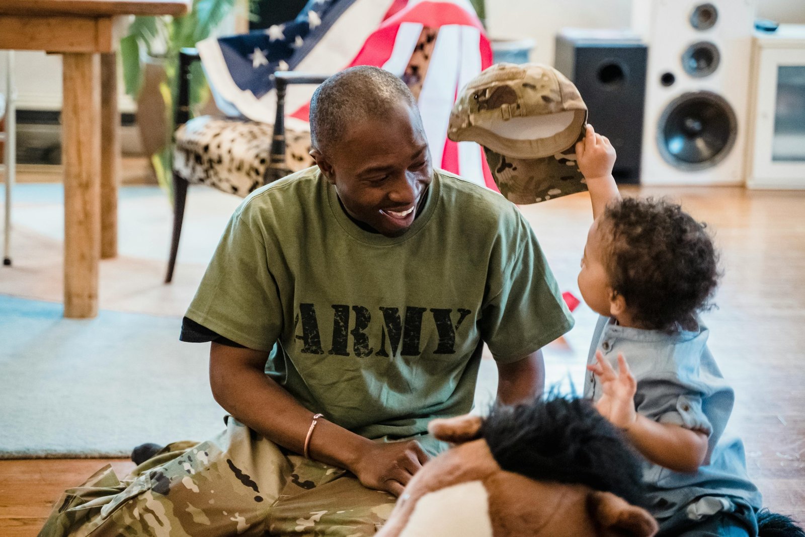 Father and young son enjoying quality time indoors with army apparel, sharing joy and love.
