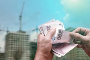 Hands clutch a stack of cash in front of a building, illustrating your trusted cash home buyers in Las Vegas, NV.