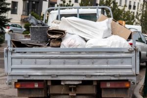 A man stands beside a truck filled with garbage, promoting junk hauling and disposal services.