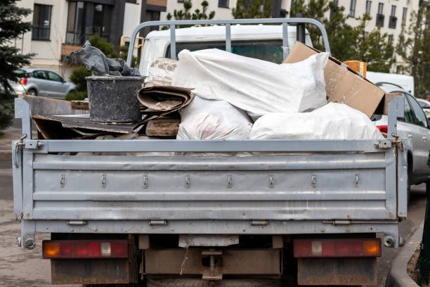 A man stands beside a truck filled with garbage, promoting junk hauling and disposal services.
