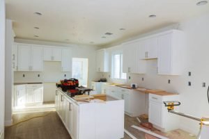 A modern kitchen featuring white cabinets and warm wood floors, showcasing custom design services in Orlando, FL.