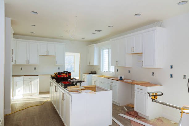 A modern kitchen featuring white cabinets and warm wood floors, showcasing custom design services in Orlando, FL.