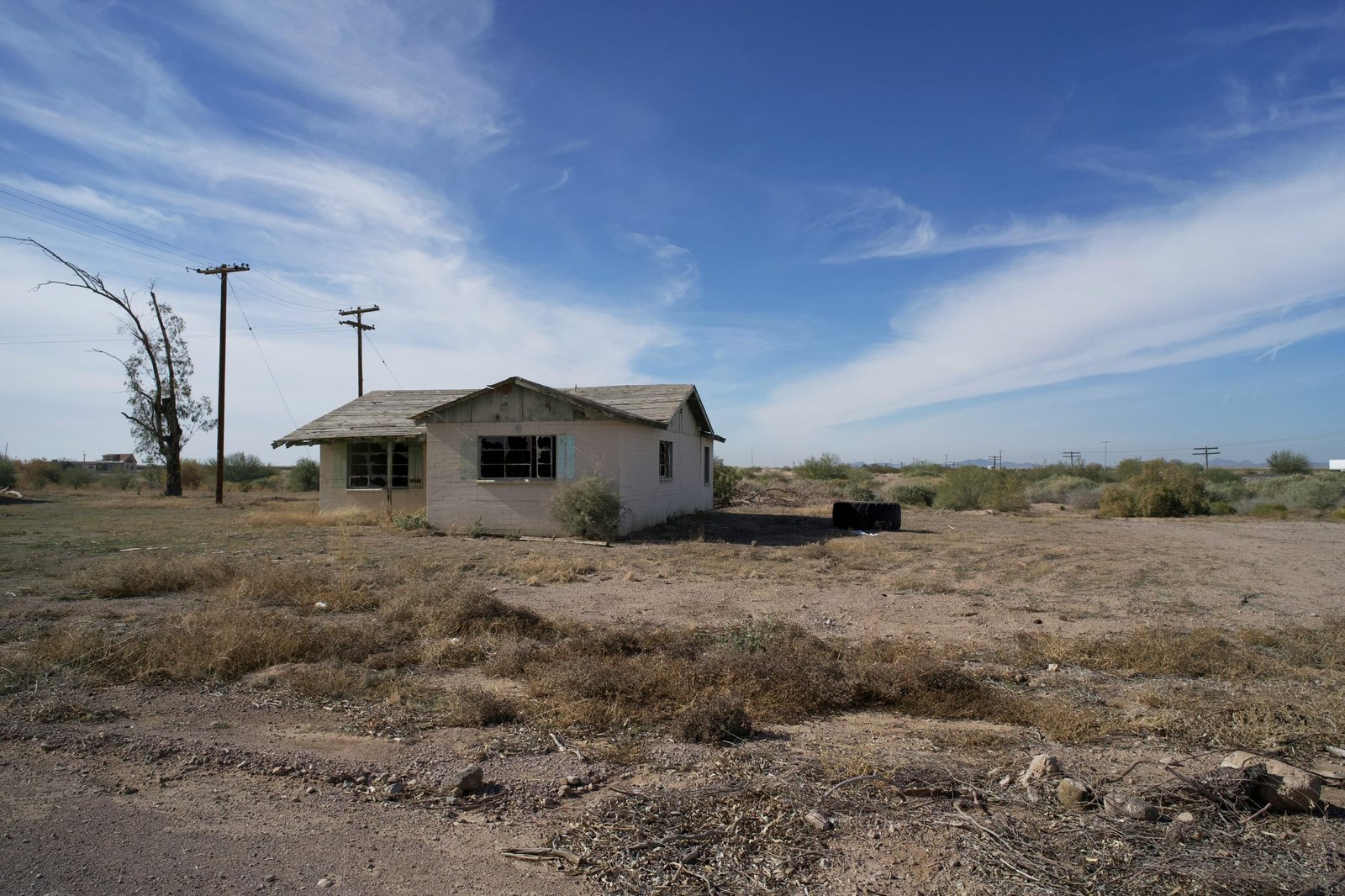 An old abandoned house in the Arizona desert with a clear blue sky background.