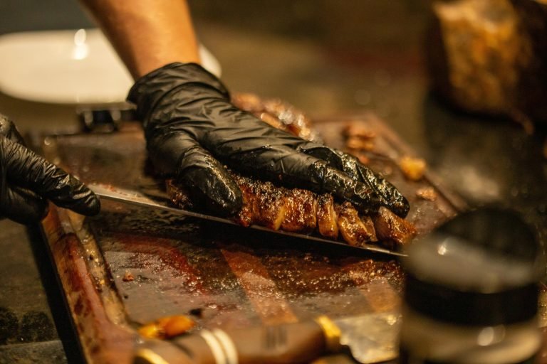 Close-up of hands slicing a juicy grilled steak on a wooden board, emphasizing culinary detail.