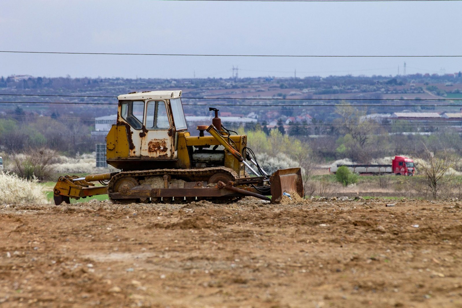 A rusty bulldozer on a construction site with a sprawling landscape view in the background.