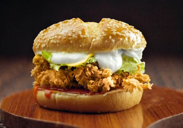 Delicious crispy chicken burger topped with fresh lettuce and creamy sauce on a sesame bun.