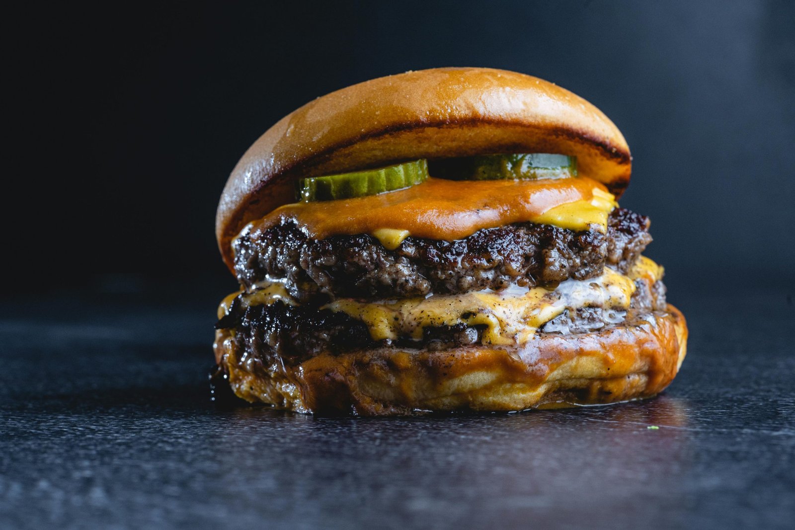 Mouth-watering beef cheeseburger with pickles, perfect for gourmet food photography.
