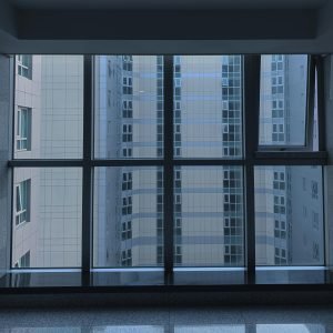 View of a modern building exterior through large windows, showcasing urban architecture.
